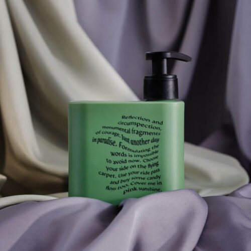 Grön flaska med Meyenberg Wild Moss and Coriander handtvål på lila tygbakgrund.