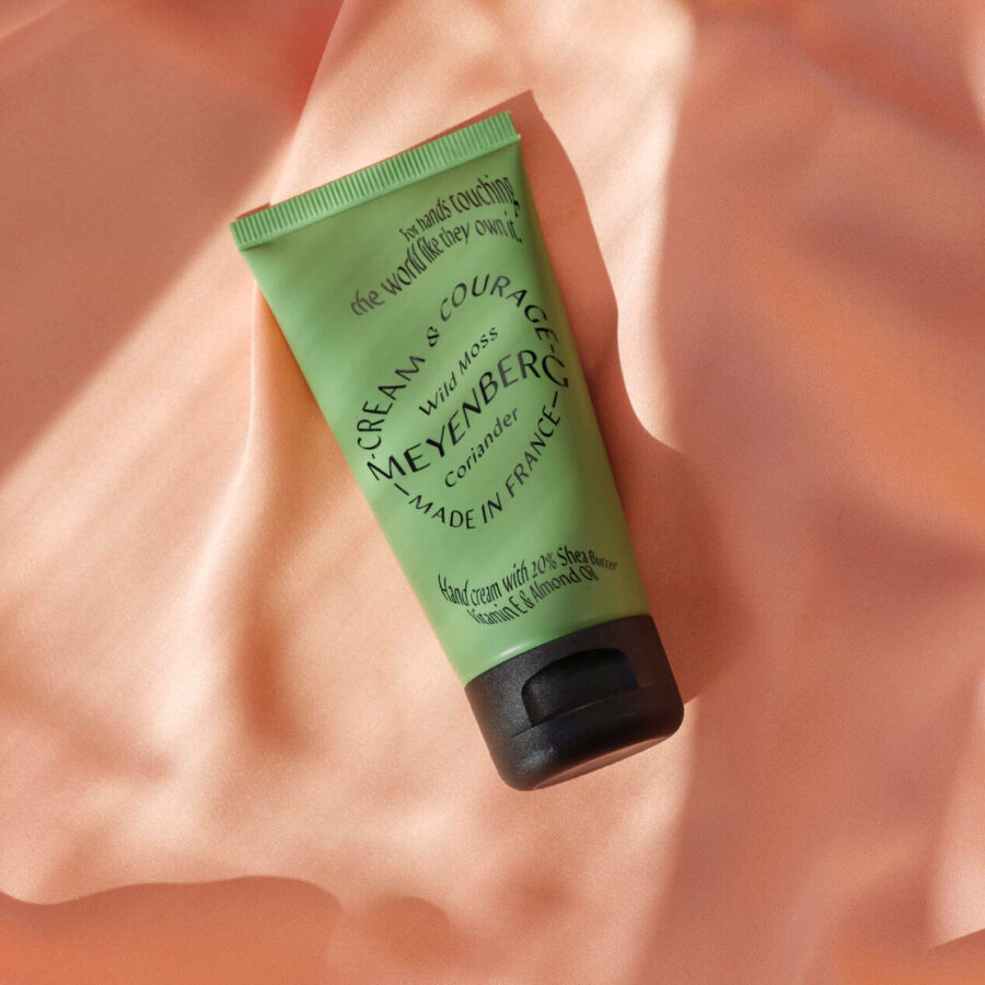 Creams and Courage handkräm i doften Wild Moss och Coriander mot persikofärgat tyg.