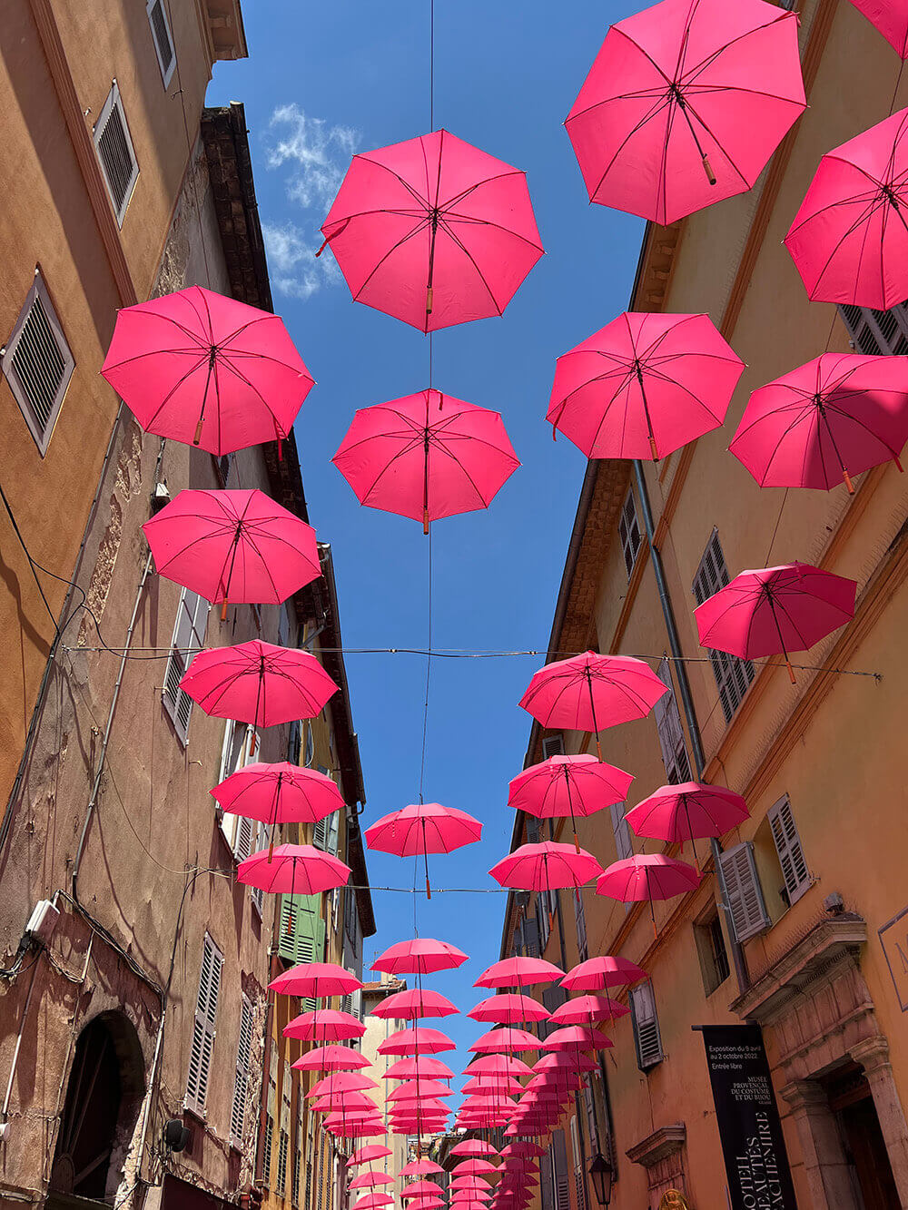Gata i Grasse med hängande rosa paraplyer.