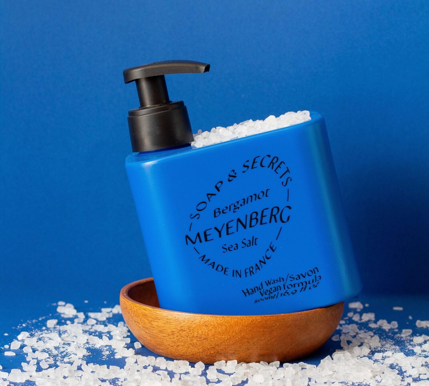 Meyenbergs blåa handtvål i doften secrets. Inramad av salt mot en blå bakgrund.