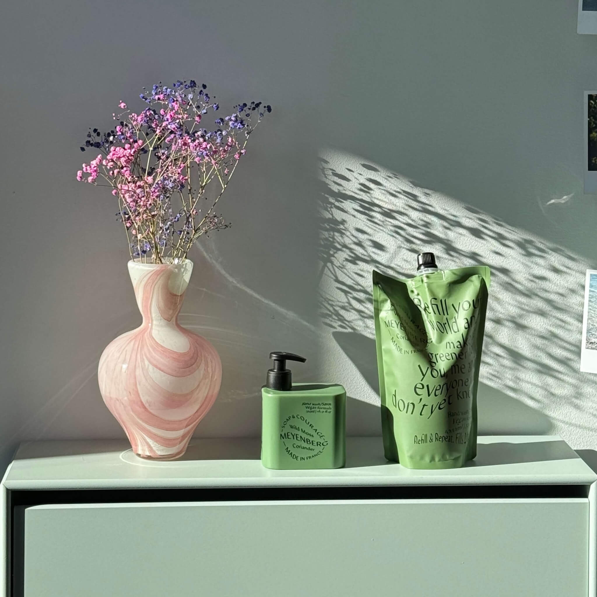 Soap and Courage handtvål och Soap and Courage refill på en grön avlastningsyta.